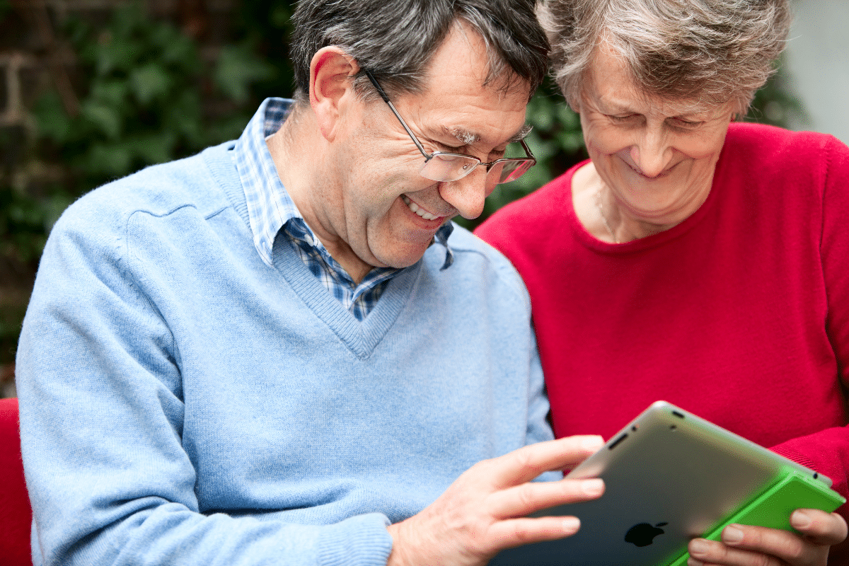man and woman smiling looking at an iPad
